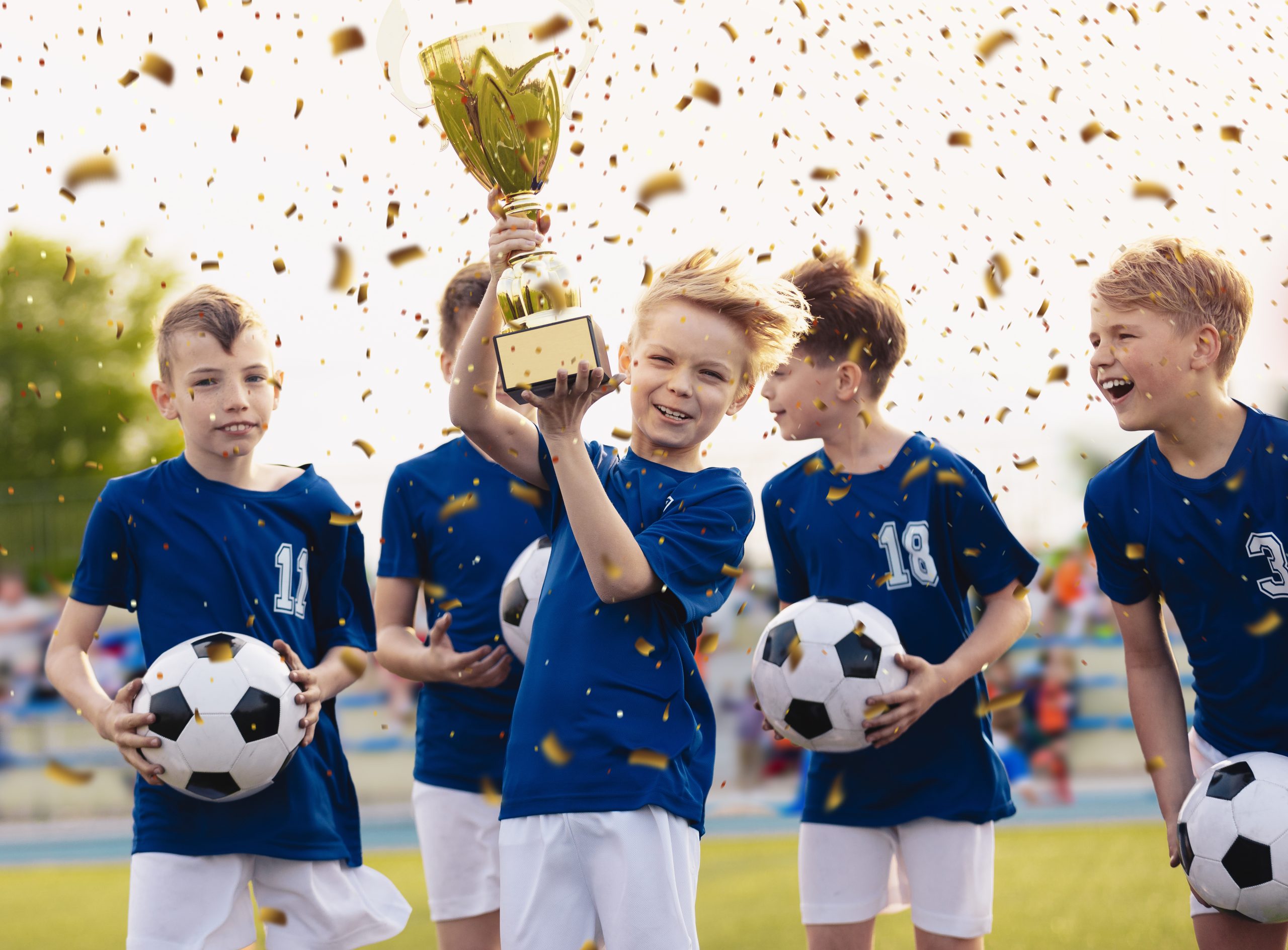 Happy kids in elementary school sports team celebrating soccer succes in tournament final game